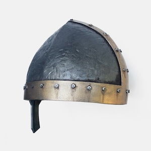 May include: A black and gold helmet with a textured surface and a band of metal rivets around the bottom edge.
