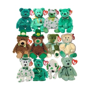 Puede incluir: Una colección de osos de peluche y un perro, en varios tonos de verde, marrón y blanco. Algunos osos visten sombreros de duende y pajaritas, mientras que otros tienen patrones de tréboles. Cada peluche tiene una etiqueta.