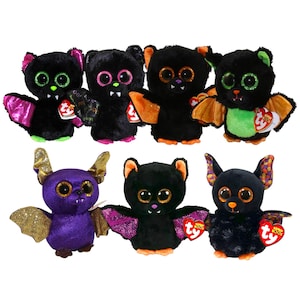 May include: A collection of plush bat toys with large, glittery eyes and colorful wings. The bats are primarily black, with accents of pink, orange, green, and gold. Each bat has a small tag attached.