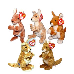 May include: Five plush kangaroo toys in various shades of brown and tan are displayed. Each kangaroo has a red heart-shaped tag. Some kangaroos have a baby kangaroo in their pouch. The toys are soft and cuddly.