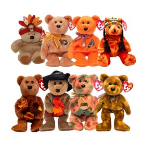 May include: A collection of eight Ty Beanie Baby bears in various colors and outfits. The bears are brown, orange, and multi-colored, with accessories like hats, ribbons, and Native American-style headbands. Each bear has a Ty heart-shaped tag.