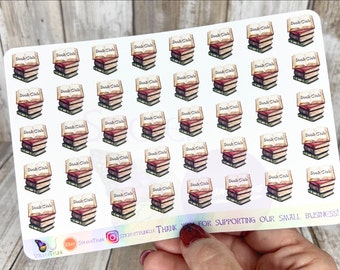 Puede incluir: Hoja de pegatinas con ilustraciones de acuarela de pilas de libros, cada una coronada con un libro abierto y las palabras "Book Club". Las pegatinas tienen un aspecto vintage, con tonos cálidos y un aspecto ligeramente desgastado.