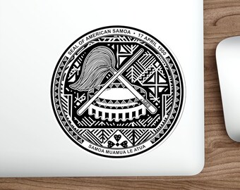 May include: A black and white sticker featuring the official seal of American Samoa. The seal depicts a crossed staff and a feathered headdress, surrounded by a geometric pattern. The text "SEAL OF AMERICAN SAMOA - 17 APRIL 1900" and "SAMOA MUAMUA LE ATUA" are inscribed around the seal.