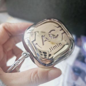 May include: Silver-colored case with a black and white logo and the name "Jimin" engraved on the front.