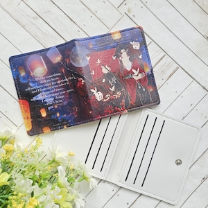 May include: A rectangular wallet featuring a dark blue and red graphic print of a character with a red umbrella, floating lanterns, and white text that reads: If I like something, then my heart will not have room for anything else. The interior is white.