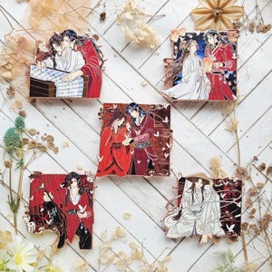 May include: Five rectangular metal enamel pins featuring anime-style characters in traditional East Asian clothing. The designs depict various scenes with red, white, and black colour palettes, including characters writing, holding lanterns, and wearing hats.