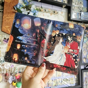 May include: A rectangular passport holder featuring a night scene with floating lanterns and two figures in traditional robes. The text reads: For you, a city full of flowers; for you, three thousand lanterns. The top right corner says Heaven Official's Blessing.