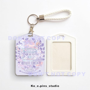 Puede incluir: Un porta-credenciales lila con un diseño floral y el texto "YOU NEVER WALK ALONE" y "WE ARE BULLETPROOF". Incluye un cordón trenzado blanco y un porta-credenciales blanco a juego.