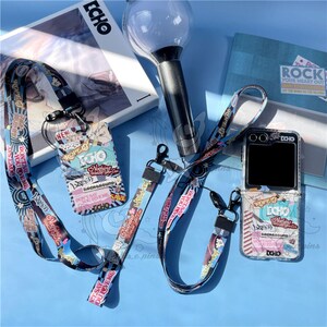 May include: A collection of accessories with a music theme, including a lanyard, phone case, and wrist strap. The items feature colorful text and graphics with the word "ECHO" and phrases like "Don't Say You Love Me". A light stick and a book are also present.