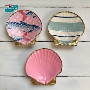 May include: Three decorative seashell dishes. One dish features a pink polka dot background with fish illustrations. Another has blue and white stripes. The third is solid pink. All have gold-painted edges. The text "NUMBER 45" is in the upper left corner.