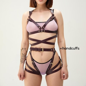 May include: A brown leather harness with gold accents and straps. The harness includes a chest piece, a waist belt, and thigh straps. The harness is worn over a purple mesh top. +handcuffs