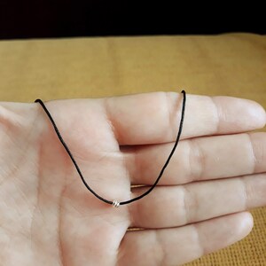 May include: A simple black cord necklace with a small silver bead accent.