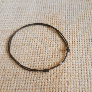 Puede incluir: Un brazalete de cordón negro con un acento de cuentas plateadas.