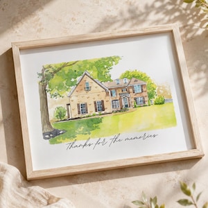 May include: Watercolor painting of a house in a light wood frame. The house is beige with brown shutters and a green lawn. The text "Thanks for the memories" is written in cursive below the house.