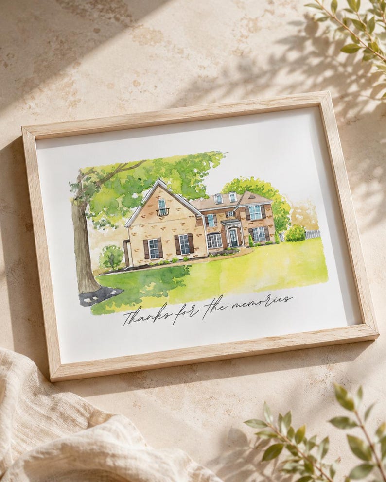 May include: Watercolor painting of a house in a light wood frame. The house is beige with brown shutters and a green lawn. The text "Thanks for the memories" is written in cursive below the house.