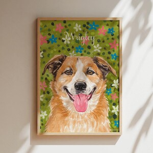 以下が含まれることがあります： 茶色と白の犬が舌を出している様子を描いた、額縁入りの長方形のウォールアートプリント。背景は緑色の野原で、小さなピンク、青、白の花が描かれています。白い筆記体でWrigleyという名前が記されています。