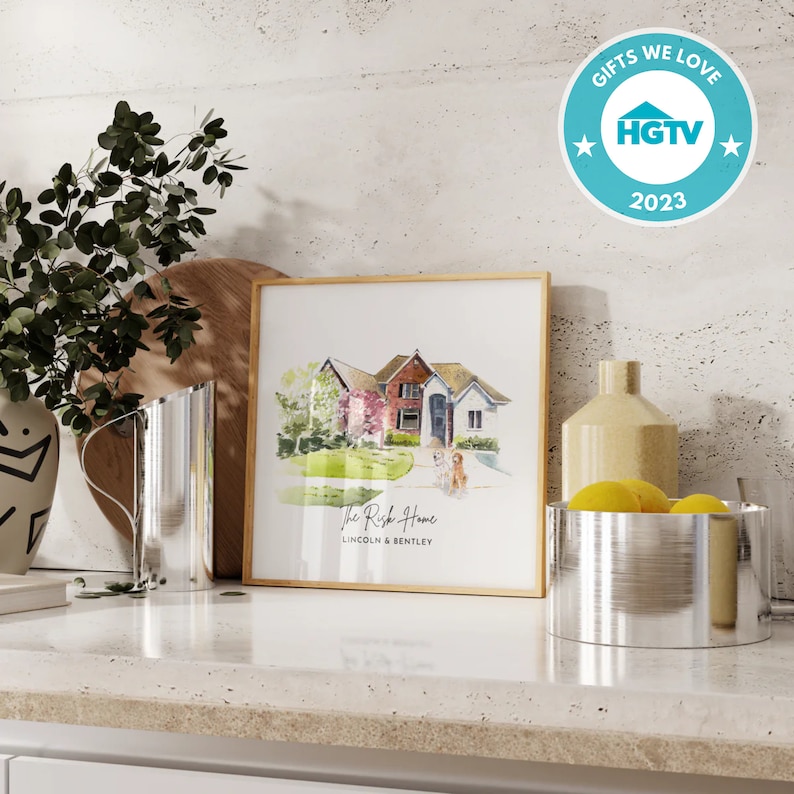 May include: A framed watercolor print of a house with a gold frame. The print is labeled "The Rich Home" with the names "Lincoln & Bentley" below. The image is on a white countertop with decorative items.