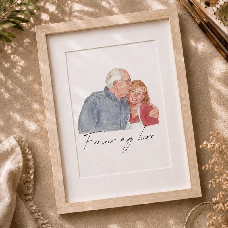 May include: A framed watercolor illustration of an older man with glasses and a woman embracing, with the text Forever my hero written in black cursive script below the figures. The artwork is enclosed in a light-colored wooden frame.