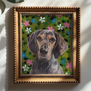 以下が含まれることがあります： 黒、茶、白の毛並みを持つハウンド犬を描いた額入り絵画。犬は、ピンク、白、青の小さな様式化された花で飾られた緑の背景の中央に配置されています。このアート作品は、金色のビーズ状のフレームに収められています。
