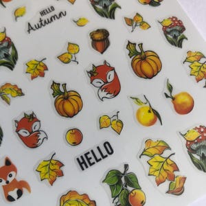 Può includere: Foglio di adesivi a tema autunnale con zucche, volpi, funghi, ghiande e foglie nei toni dell'arancione, giallo e verde. Sono incluse anche le parole "Hello Autumn" e "Hello".