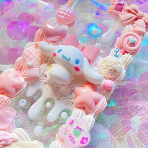 May include: A white and pink character with a bow on its head, surrounded by pink and white hearts, stars, and other decorations. The character is on a white background with a pink and white swirl design.