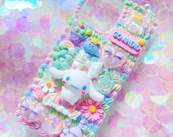 Può includere: Una custodia per telefono color pastello decorata con decorazioni 3D, tra cui un cane bianco dei cartoni animati, fiori, un castello, un fiocco e un cartello che dice "Go Ahead".