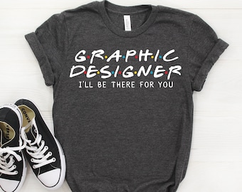 May include: Dark gray t-shirt with white text that reads "GRAPHIC DESIGNER I'LL BE THERE FOR YOU" in a font reminiscent of the popular TV show "Friends".