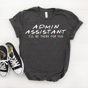 May include: Dark grey t-shirt with white text that reads "Admin Assistant I'll be there for you" in a font style reminiscent of the popular TV show "Friends".