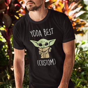 May include: Black t-shirt with a white graphic of a green baby Yoda character with the text "Yoda Best (Custom)"