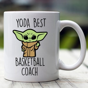 May include: White ceramic coffee mug with a green cartoon character and the text "YODA BEST BASKETBALL COACH".