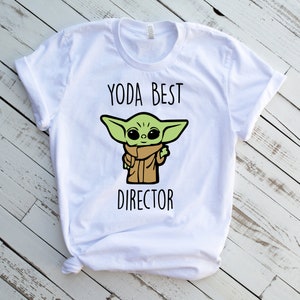 May include: White t-shirt with a green cartoon character and the text "Yoda Best Director".