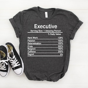 May include: A dark grey t-shirt with a white graphic that reads "Executive" and lists the percentage of daily value for hard work, passion, determination, pride, respect, caffeine, and regret.
