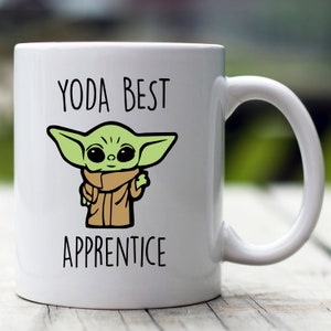 May include: White ceramic mug with a green cartoon character and the text "YODA BEST APPRENTICE".