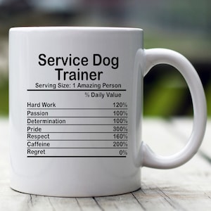 May include: White ceramic mug with a black graphic that reads "Service Dog Trainer" and a nutrition facts label listing "Hard Work", "Passion", "Determination", "Pride", "Respect", "Caffeine", and "Regret" with percentages next to each.