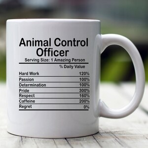Könnte beinhalten: Weiße Keramik-Tasse mit dem Text "Animal Control Officer" in Schwarz. Die Tasse enthält ein Nährwertetikett mit Werten für harte Arbeit, Leidenschaft, Entschlossenheit, Stolz, Respekt, Koffein und Bedauern.