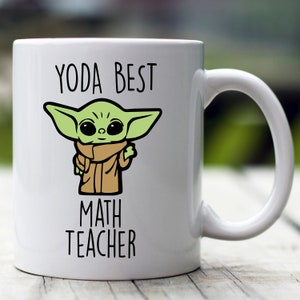 May include: White ceramic mug featuring a green cartoon character and the text "YODA BEST MATH TEACHER".