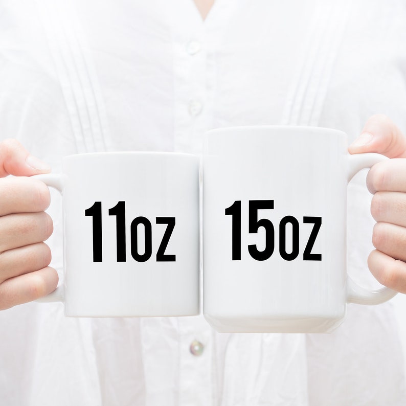 K&ouml;nnte beinhalten: Zwei wei&szlig;e Keramikbecher mit schwarzem Text. Der Becher links zeigt "11oz" und der Becher rechts zeigt "15oz".
