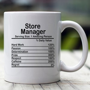 以下が含まれることがあります： 大きな取っ手が付いた白いセラミックマグ。マグには「Store Manager」の文字と、「Hard Work」、「Passion」、「Caffeine」などの毎日の価値のリストが記載されています。マグは栄養成分表示のようにデザインされています。