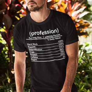 May include: Black t-shirt with the text "(profession)" and a nutrition facts label listing qualities like "Hard Work" and "Passion." The shirt's design is in white, and the model is wearing sunglasses.
