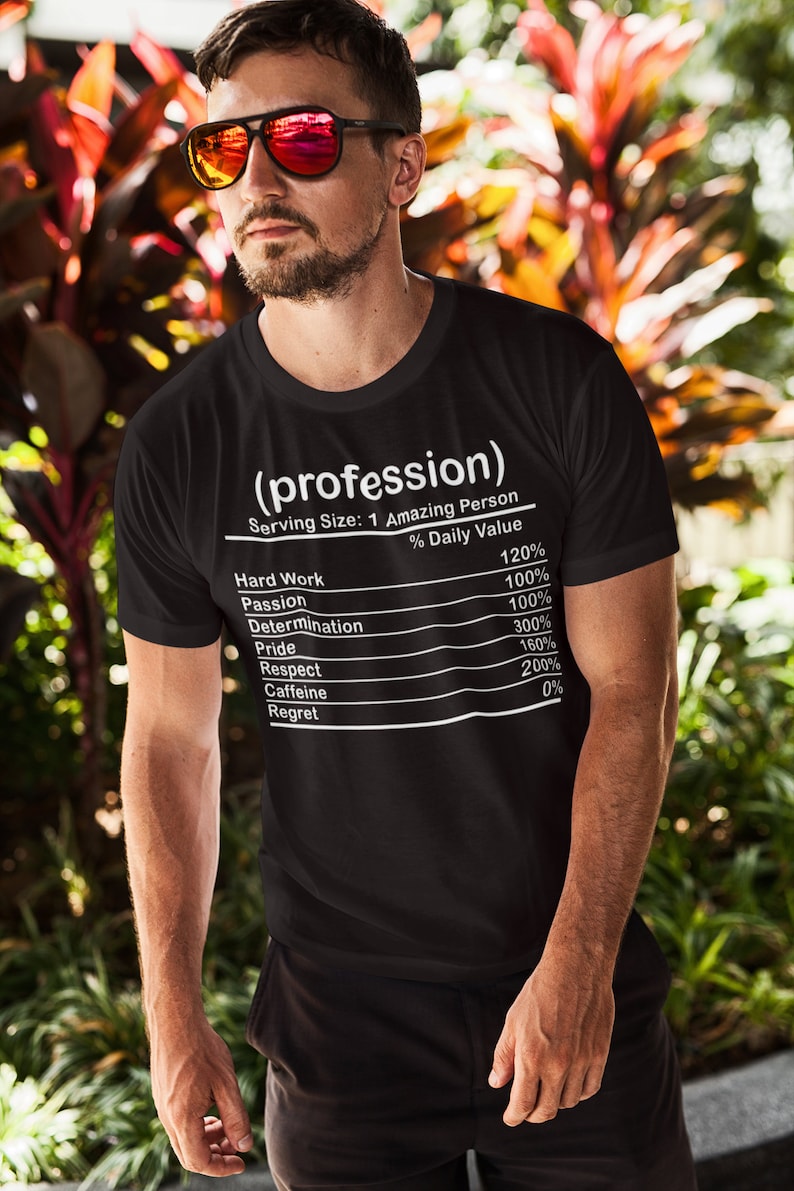 May include: Black t-shirt with the text "(profession)" and a nutrition facts label listing qualities like "Hard Work" and "Passion." The shirt's design is in white, and the model is wearing sunglasses.