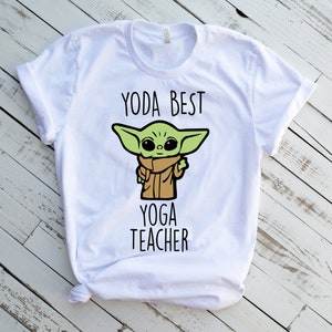 May include: White t-shirt with a green cartoon character and the text "Yoda Best Yoga Teacher".