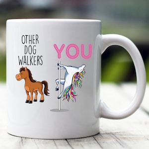 May include: White ceramic mug with a pink and black graphic. The graphic says "Other Dog Walkers" with a cartoon horse on the left and "You" with a cartoon unicorn on the right. The unicorn is holding onto a pole.