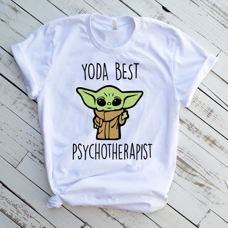 May include: White t-shirt with a green cartoon character and the text "Yoda Best Psychotherapist".