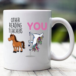 May include: White ceramic coffee mug with a pink and black graphic. The graphic says "Other Reading Teachers" with a brown horse on the left and "You" with a unicorn on a pole on the right.