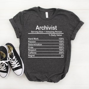 May include: A dark gray t-shirt with the text "Archivist" and a nutrition facts label listing the percentage of daily value for hard work, passion, determination, pride, respect, caffeine, and regret.