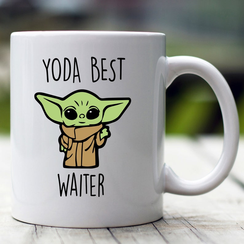 Peut inclure: Une tasse en c&eacute;ramique blanche avec un personnage de dessin anim&eacute; vert et le texte "YODA BEST WAITER".