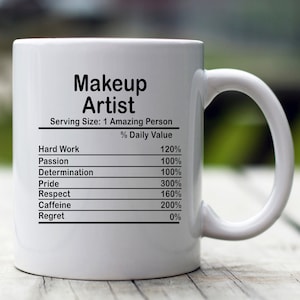 May include: White ceramic mug with a black graphic that reads "Makeup Artist" and lists the daily value of hard work, passion, determination, pride, respect, caffeine, and regret.