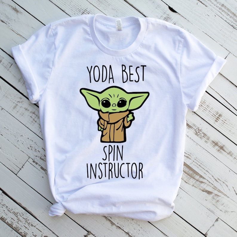 K&ouml;nnte beinhalten: Wei&szlig;es T-Shirt mit einer gr&uuml;nen Comicfigur und dem Text "Yoda Best Spin Instructor".