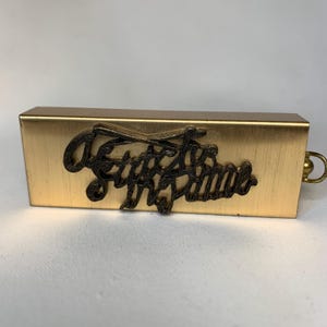 May include: A gold metal box with a black inscription that reads "Keep the Faith".