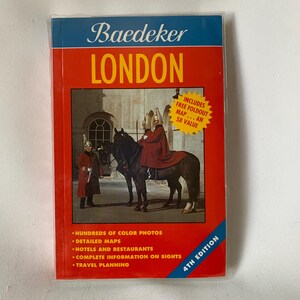 May include: A red and white travel guide book with the title "Baedeker London" and a picture of a red-coated mounted guard on a black horse. The book includes hundreds of color photos, detailed maps, information on hotels and restaurants, and travel planning tips. It also includes a free foldout map.